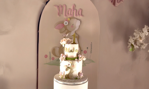 Pastel children’s celebration cake with bunny details, soft florals, and custom topper