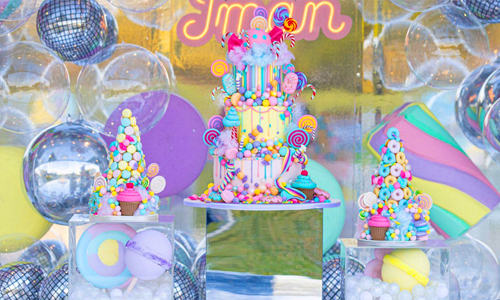 Vibrant candy-themed birthday cake with lollipops and bright party décor.