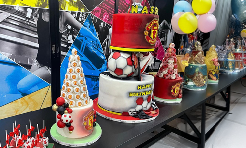 Manchester United cake with football, sneakers and sports-inspired decorations.