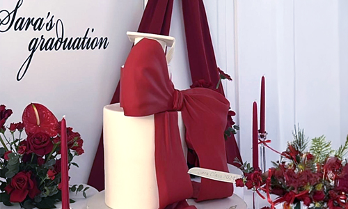 Graduation custom cake featuring a large decorative bow, smooth fondant finish, and elegant styling for graduation celebrations. Cute and Coquette