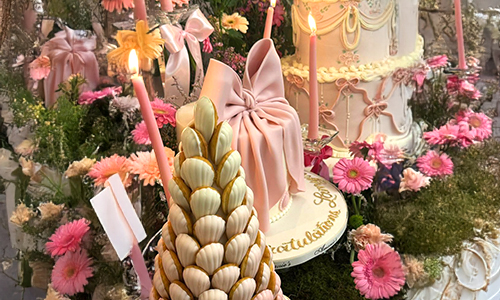 Decorated cakes and sweet corner with pink bow cake, florals, candles, and macaron tower.Coquette Aesthetic